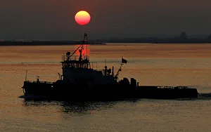 A boat sails as the sun sets over the place of a confluence of Angara and Yenisei rivers A boat sails as the sun sets over the place of a confluence of Angara and Yenisei rivers