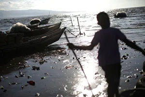 A boy plays with a stick next to row boats anchored on the shore in Port-au-Prince A boy plays with a stick next to row boats anchored on the shore in Port-au-Prince