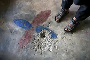 A boy stands next to a crater on the floor of his house A boy stands next to a crater on the floor of his house