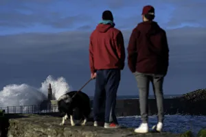 Two boys look at waves as they crash against a lighthouse in the port town of Viavelez Two boys look at waves as they crash against a lighthouse in the port town of Viavelez
