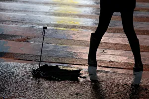A broken umbrella is seen on the ground as a woman passes by it in Times Square during a A broken umbrella is seen on the ground as a woman passes by it in Times Square during a