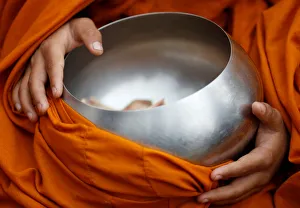 A Buddhist monk holding a vessel sits at the premises of Boudhanath Stupa while waiting A Buddhist monk holding a vessel sits at the premises of Boudhanath Stupa while waiting
