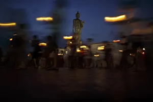 Buddhists holding candles encircle a large Buddha statue during Makha Bucha Day at a Buddhists holding candles encircle a large Buddha statue during Makha Bucha Day at a