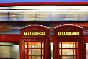 A bus passes traditional telephone boxes in London A bus passes traditional telephone boxes in London