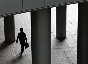 A businessman walks past pillars in Tokyo A businessman walks past pillars in Tokyo