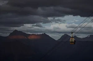 A cable car is pictured with Caucasus mountains during sunset in the background outside A cable car is pictured with Caucasus mountains during sunset in the background outside