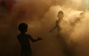 Children of local residents play through an area being fumigated by municipal workers at Children of local residents play through an area being fumigated by municipal workers at
