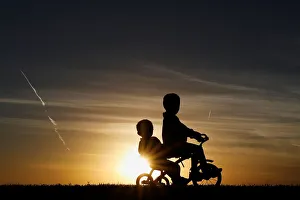 Children are seen in silhouette riding a tricycle along the Mississippi River Park at Children are seen in silhouette riding a tricycle along the Mississippi River Park at