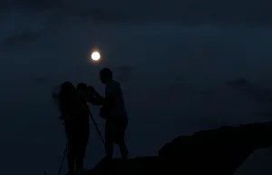 A couple takes a picture of the supermoon rising over Ischigualasto Provincial Park in A couple takes a picture of the supermoon rising over Ischigualasto Provincial Park in