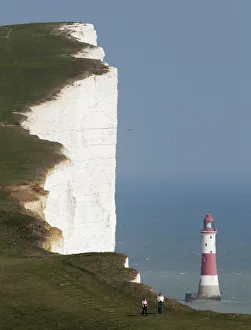 A couple walk along the Seven Sisters cliffs close to the Beachy Head lighthouse near Eastbourne A couple walk along the Seven Sisters cliffs close to the Beachy Head lighthouse near Eastbourne