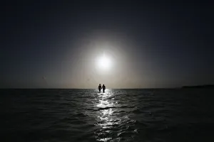 A couple walks on a sandbar in the shallow sea at an archipelago of Los Roques A couple walks on a sandbar in the shallow sea at an archipelago of Los Roques