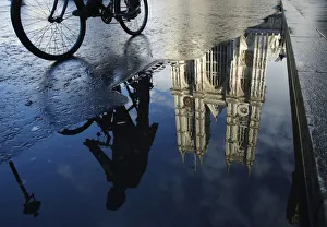 A cyclist is reflected in a puddle as he passes Westminster Abbey in London A cyclist is reflected in a puddle as he passes Westminster Abbey in London