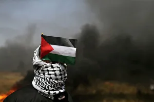 Demonstrator with a Palestinian flag looks on during clashes with Israeli troops at the Demonstrator with a Palestinian flag looks on during clashes with Israeli troops at the