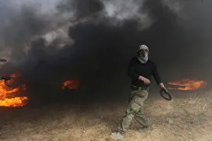 Demonstrator passes by burning tires during clashes with Israeli troops at a protest Demonstrator passes by burning tires during clashes with Israeli troops at a protest