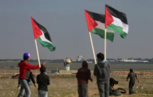 Demonstrators hold Palestinian flags during clashes with Israeli troops near the border Demonstrators hold Palestinian flags during clashes with Israeli troops near the border