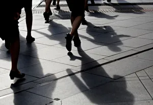 Female office workers wearing high heels and clothes of the same colour walk at a Female office workers wearing high heels and clothes of the same colour walk at a