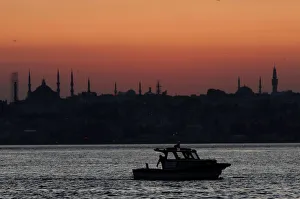 A fishing boat sails in the Bosphorus as the sun sets over the old city in Istanbul A fishing boat sails in the Bosphorus as the sun sets over the old city in Istanbul
