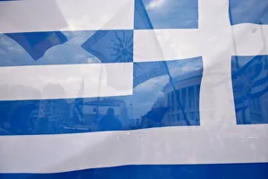 A flag depicting Vergina sun is seen through a Greek flag during a demonstration against A flag depicting Vergina sun is seen through a Greek flag during a demonstration against