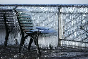 A frozen public bench is seen next to a lake side due to the heavy wind conditions A frozen public bench is seen next to a lake side due to the heavy wind conditions