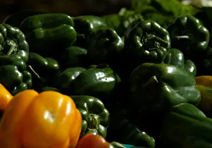 Green and yellow peppers are displayed on a vendors stand at the Farmers Market in Ta Green and yellow peppers are displayed on a vendors stand at the Farmers Market in Ta