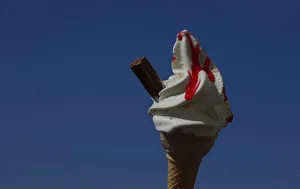 An ice cream cone is held against a blue sky in Blackpool An ice cream cone is held against a blue sky in Blackpool