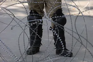 An Indian police officer stands behind the concertina wire during restrictions An Indian police officer stands behind the concertina wire during restrictions