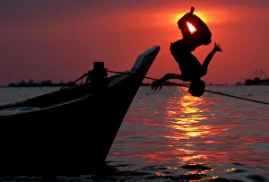 Indonesian boys do somersaults from a wooden boat in Jakartas shore Indonesian boys do somersaults from a wooden boat in Jakartas shore