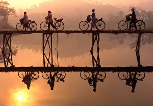 Indonesian villagers push their bicycles across a bamboo bridge as sun rises behind them outside Indonesian villagers push their bicycles across a bamboo bridge as sun rises behind them outside