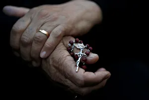 An Iraqi Christian woman holds a cross during a prayer session inside the Syriac Orthodox An Iraqi Christian woman holds a cross during a prayer session inside the Syriac Orthodox