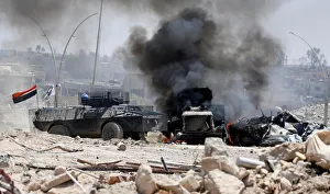 An Iraqi military armoured fighting vehicle (AFV) drives past a burning Iraqi military An Iraqi military armoured fighting vehicle (AFV) drives past a burning Iraqi military