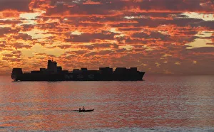 Kayakers take in the last of the days light as they paddle past a ship anchored off Kayakers take in the last of the days light as they paddle past a ship anchored off
