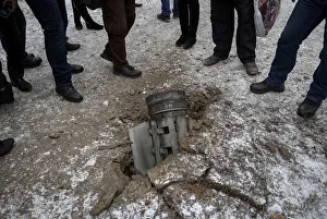 Local residents look at the remains of a rocket shell on a street in the town of Local residents look at the remains of a rocket shell on a street in the town of