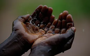 A Malawian child catches raindrops during a brief downpour in Ngozi village near the A Malawian child catches raindrops during a brief downpour in Ngozi village near the