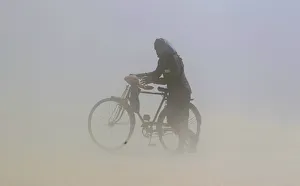 A man covers his face as he pushes a bicycle through a dust storm on the banks of the A man covers his face as he pushes a bicycle through a dust storm on the banks of the
