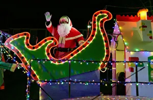 A man dressed as Santa Claus waves from a truck decorated in lights as it makes its A man dressed as Santa Claus waves from a truck decorated in lights as it makes its