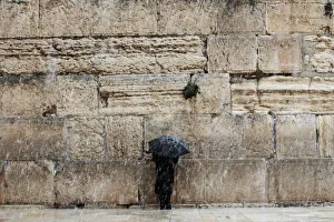 A man holding an umbrella prays at the Western Wall in Jerusalems Old City during a A man holding an umbrella prays at the Western Wall in Jerusalems Old City during a