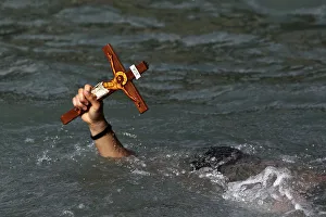 A man holds a cross after a competition to retrieve it from the water during Epiphany day A man holds a cross after a competition to retrieve it from the water during Epiphany day
