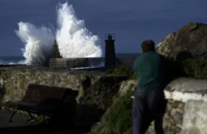 A man looks at waves as they crash against a lighthouse in the port town of Viavelez A man looks at waves as they crash against a lighthouse in the port town of Viavelez