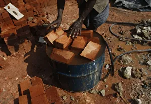 A man puts bricks into an oil barrel which filled with water at a construction site in A man puts bricks into an oil barrel which filled with water at a construction site in