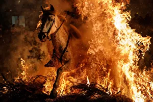 A man rides a horse through flames during the annual Luminarias celebration on the eve A man rides a horse through flames during the annual Luminarias celebration on the eve