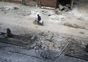 A man rides on a motorbike at a damaged site in the rebel held besieged town of A man rides on a motorbike at a damaged site in the rebel held besieged town of