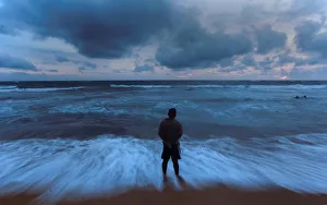 A man stands on a beach before the rain during the monsoon season in Colombo A man stands on a beach before the rain during the monsoon season in Colombo