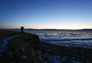 A man takes pictures from a bank of the frozen Yenisei River outside the village of A man takes pictures from a bank of the frozen Yenisei River outside the village of