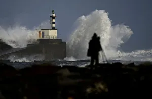 Man takes pictures of waves crashing at the San Esteban de Pravia seafront of the Spanish Man takes pictures of waves crashing at the San Esteban de Pravia seafront of the Spanish