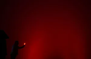 A man tries to take a photo of the Christ the Redeemer statue lit up in red to mark World A man tries to take a photo of the Christ the Redeemer statue lit up in red to mark World