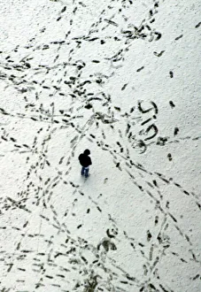 A MAN WALKS AMONG FOOTPRINTS IN THE SNOW COVERED OLYMPIC PARK IN MUNICH A MAN WALKS AMONG FOOTPRINTS IN THE SNOW COVERED OLYMPIC PARK IN MUNICH