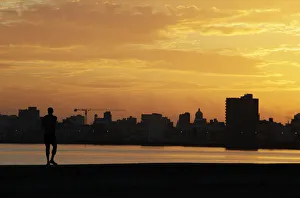 A man walks on Havanas seafront boulevard El Malecon at dawn in Havana A man walks on Havanas seafront boulevard El Malecon at dawn in Havana