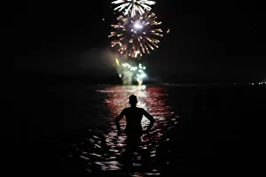 A man watches fireworks as he takes a bath in the Mediterranean Sea on San Juans night A man watches fireworks as he takes a bath in the Mediterranean Sea on San Juans night