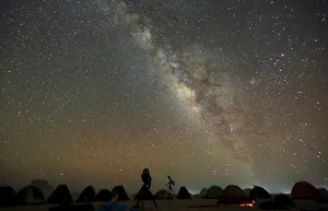 The Milky Way is seen in the night sky around telescopes and camps of people over The Milky Way is seen in the night sky around telescopes and camps of people over