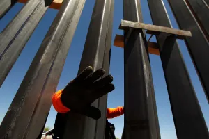 A private security guard blocks the camera at a bollard wall in New Mexico